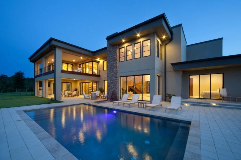 Modern two-story new construction home with illuminated pool at dusk in Tampa Bay